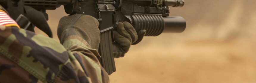 Close-up of a soldier in camo firing a rifle in action during training.